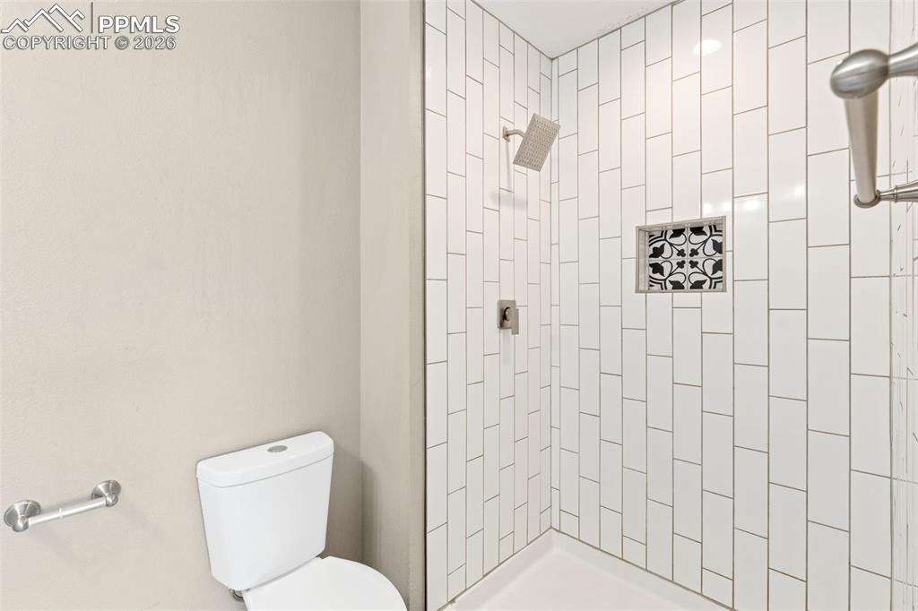 Image 15 of 26: Updated master bath with tile floor, double vanity, and tile shower.