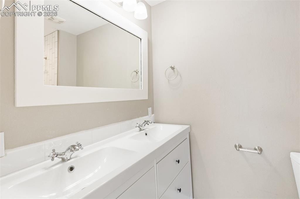 Image 16 of 26: Updated master bath with tile floor, double vanity, and tile shower.