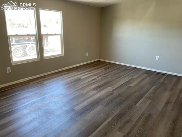 Image 14 of 21: Empty room with a textured ceiling and dark wood-type flooring