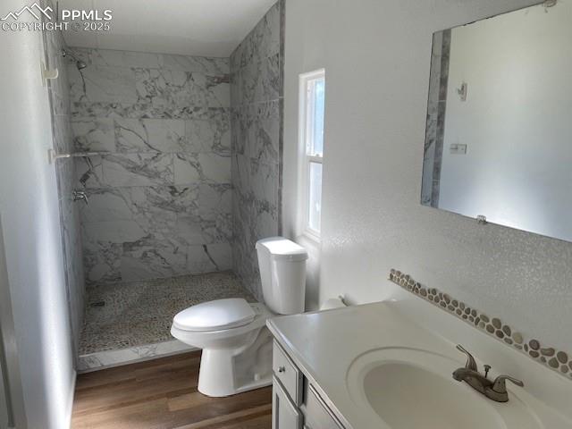 Image 18 of 21: Bathroom featuring vanity, tiled shower, and wood finished floors