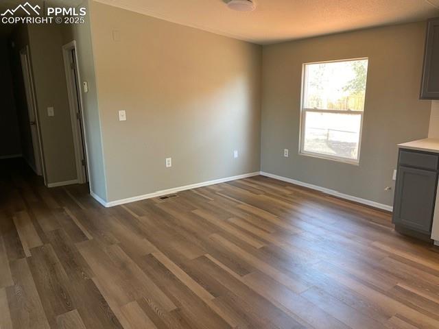 Image 4 of 21: Unfurnished dining area with dark wood-style floors and a textured ceiling