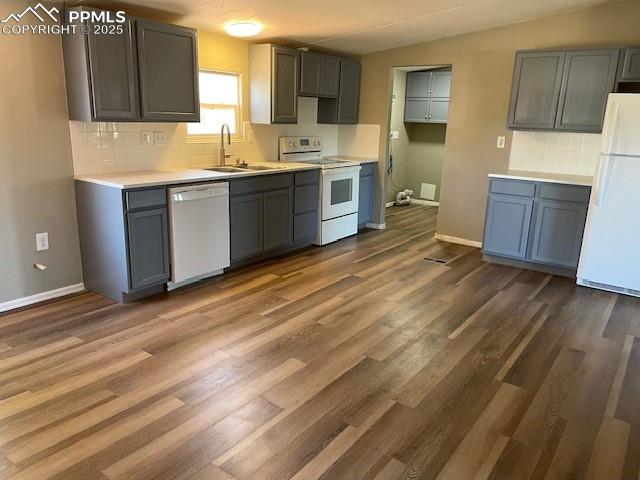 Image 6 of 21: Kitchen with decorative backsplash, white appliances, gray cabinets, dark w