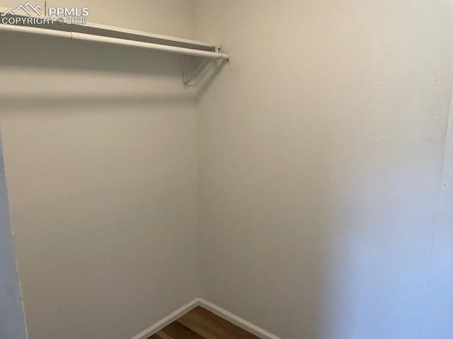Image 9 of 21: Walk in closet with dark wood-style flooring