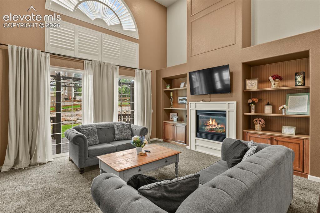 Image 10 of 47: Living area featuring a fireplace with a white mantel, built-in shelving, a
