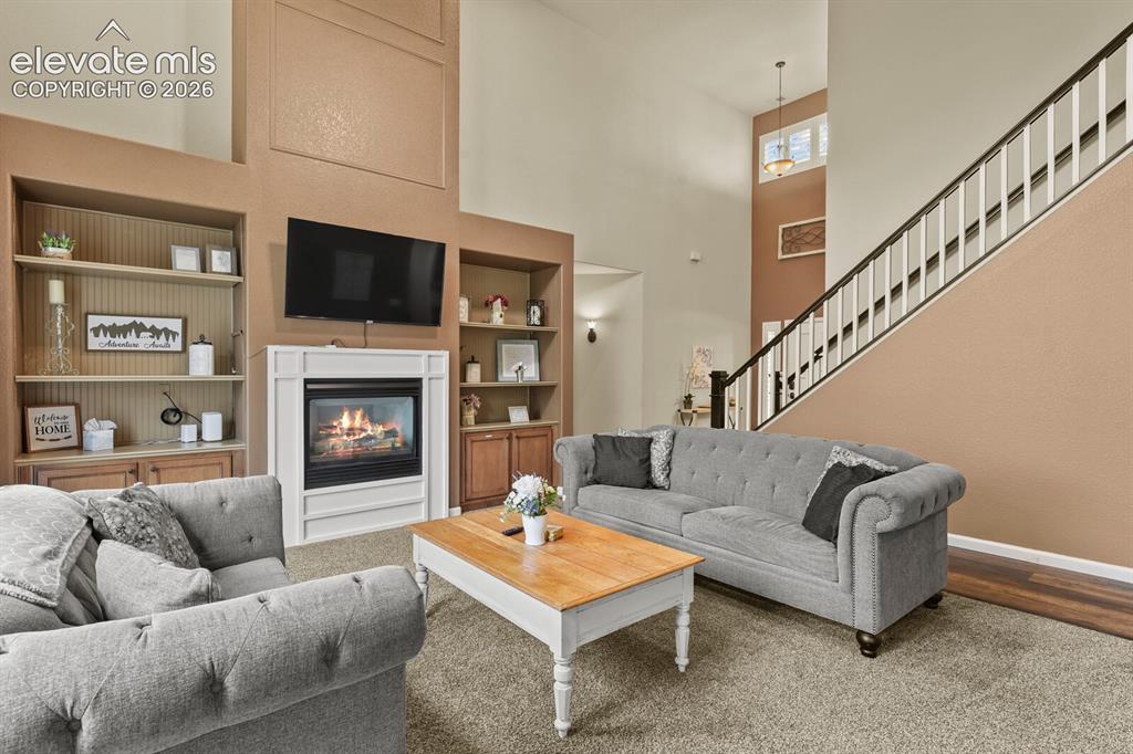 Image 13 of 47: Living room featuring a fireplace with a white mantel, built-in shelving, h