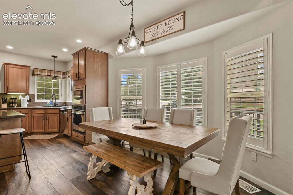 Image 14 of 47: Dining area featuring a decorative chandelier, white plantation shutters, a