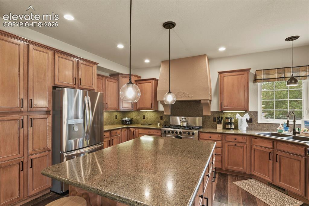 Image 15 of 47: Kitchen featuring a central island with a stone countertop, extensive wood 