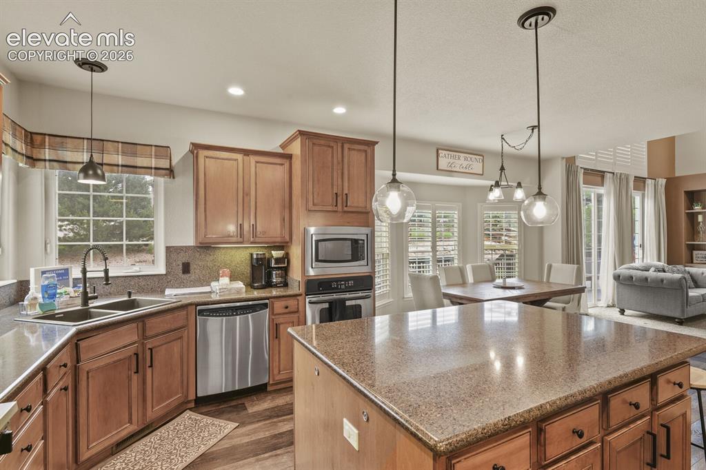 Image 17 of 47: Kitchen featuring a central island with stone-finish countertop, wood-finis