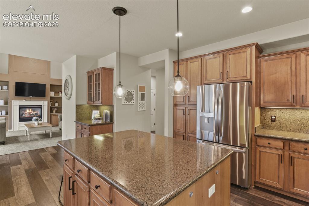 Image 18 of 47: Kitchen island featuring a speckled countertop and pendant lighting