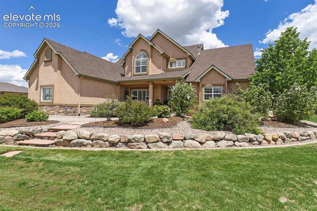 Image 2 of 47: Stucco exterior residence featuring a stone-clad foundation and a multi-lev