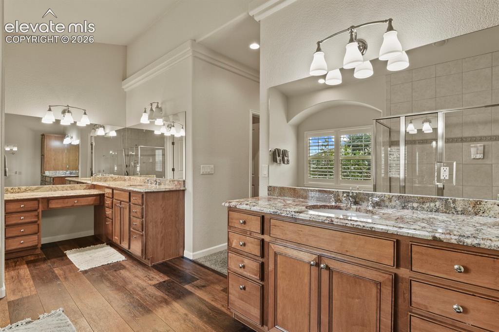 Image 22 of 47: Spacious bathroom featuring rich wood cabinetry, stone countertops, dual si