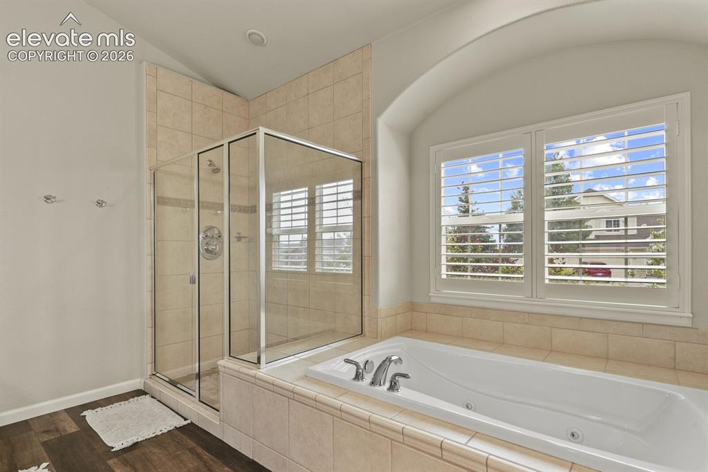 Image 23 of 47: Soaking tub with jetted features set into a tiled surround, framed by an ar