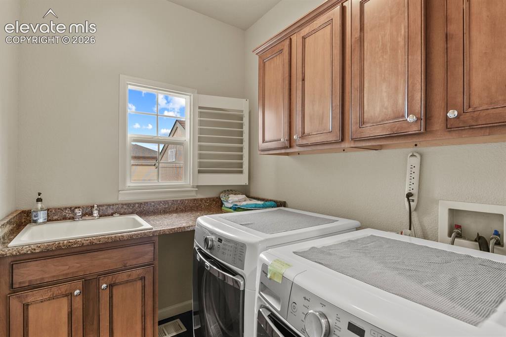 Image 24 of 47: Utility room featuring wood-finish cabinetry, a drop-in sink, a granite-loo