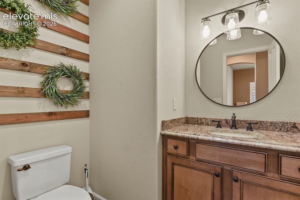 Image 25 of 47: Bathroom vanity with a stone countertop, an undermount sink, and dark wood 