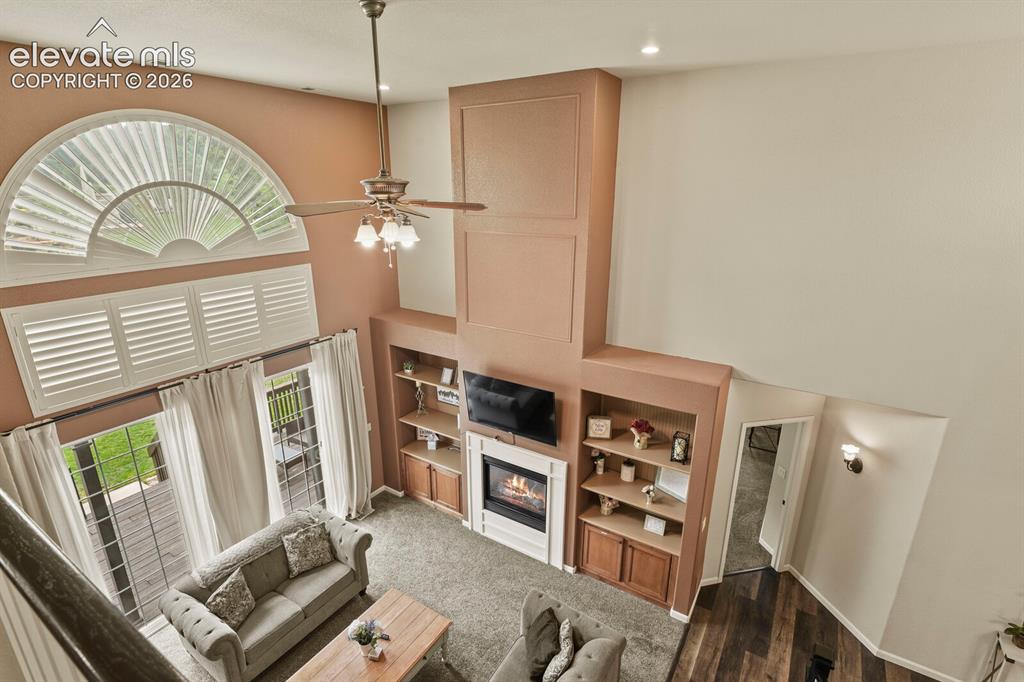 Image 26 of 47: Vaulted living space featuring a fireplace with white mantel, custom built-