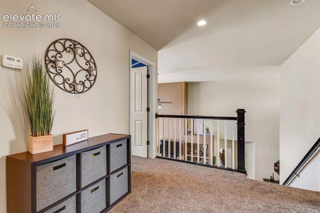 Image 27 of 47: Carpeted landing featuring a white baluster railing with a dark newel post 