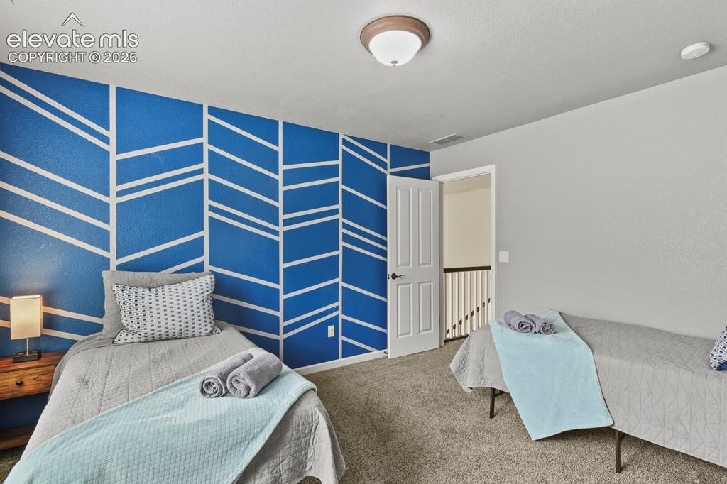 Image 32 of 47: Bedroom featuring an accent wall with a geometric pattern, wall-to-wall car