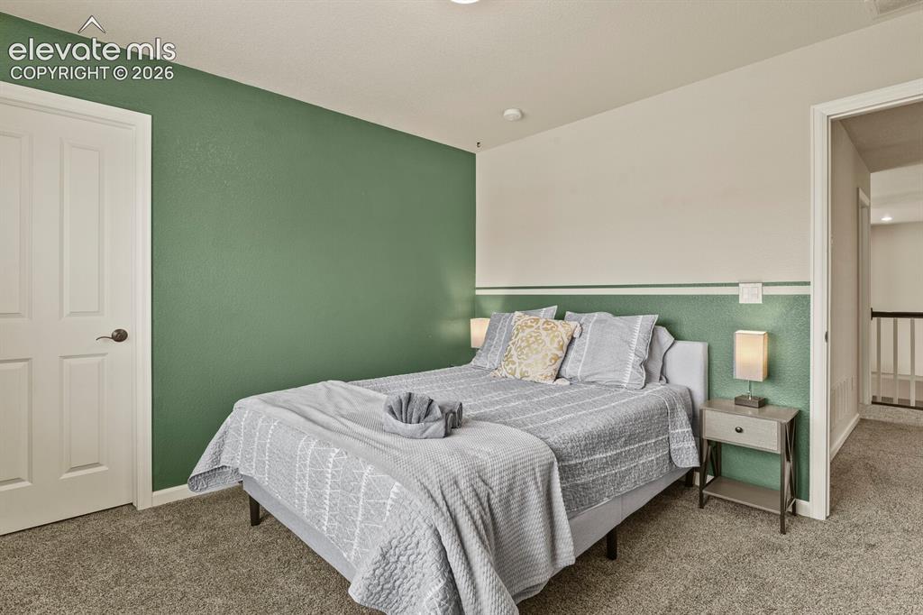 Image 34 of 47: Carpeted bedroom featuring a two-tone accent wall and a paneled white door