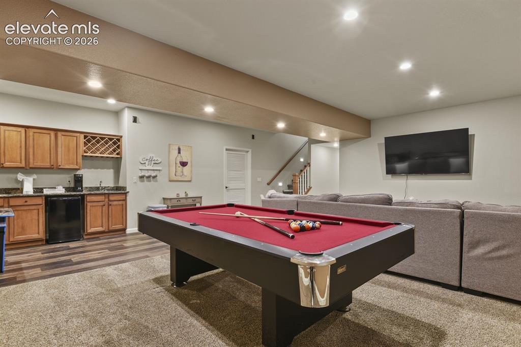 Image 37 of 47: Spacious entertainment area featuring recessed lighting and a wet bar with 