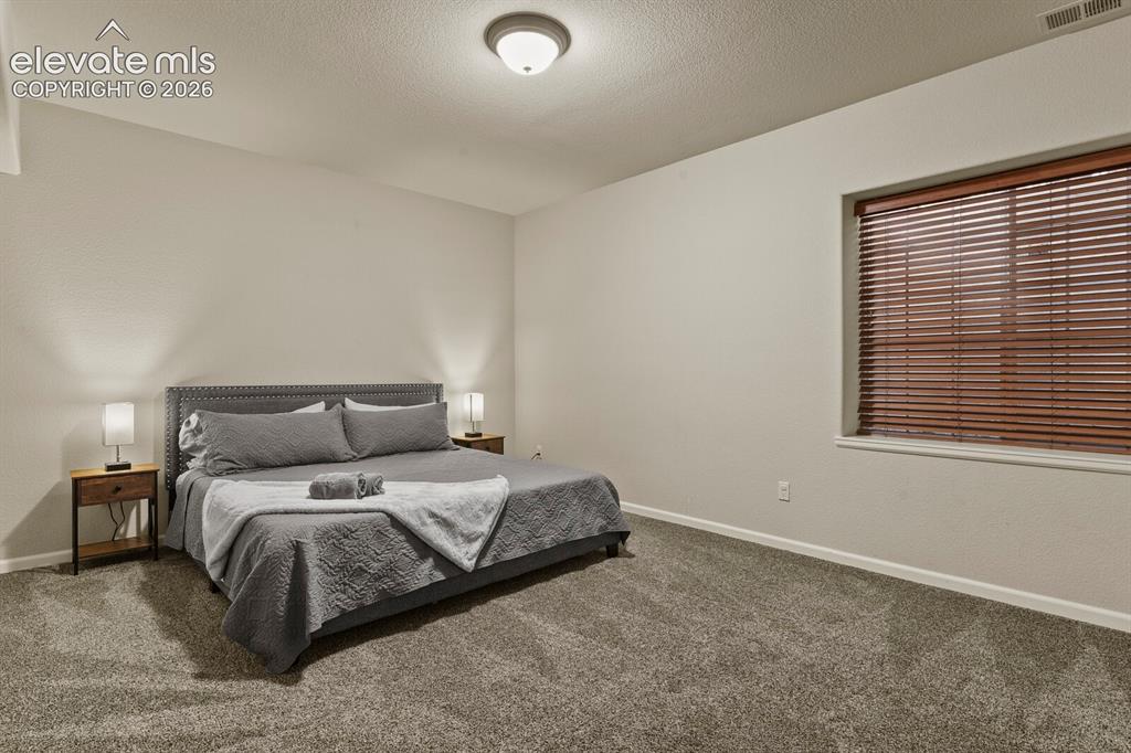 Image 40 of 47: Carpeted bedroom featuring a vaulted ceiling and textured walls