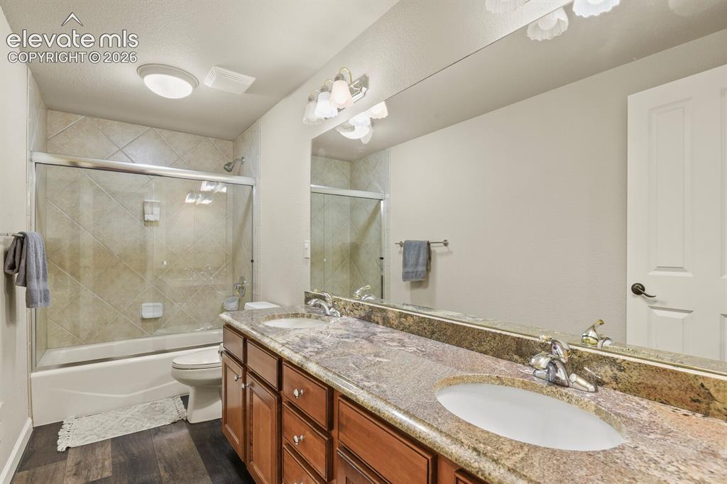 Image 42 of 47: Bathroom featuring a dual vanity with a granite countertop, wood-finish cab