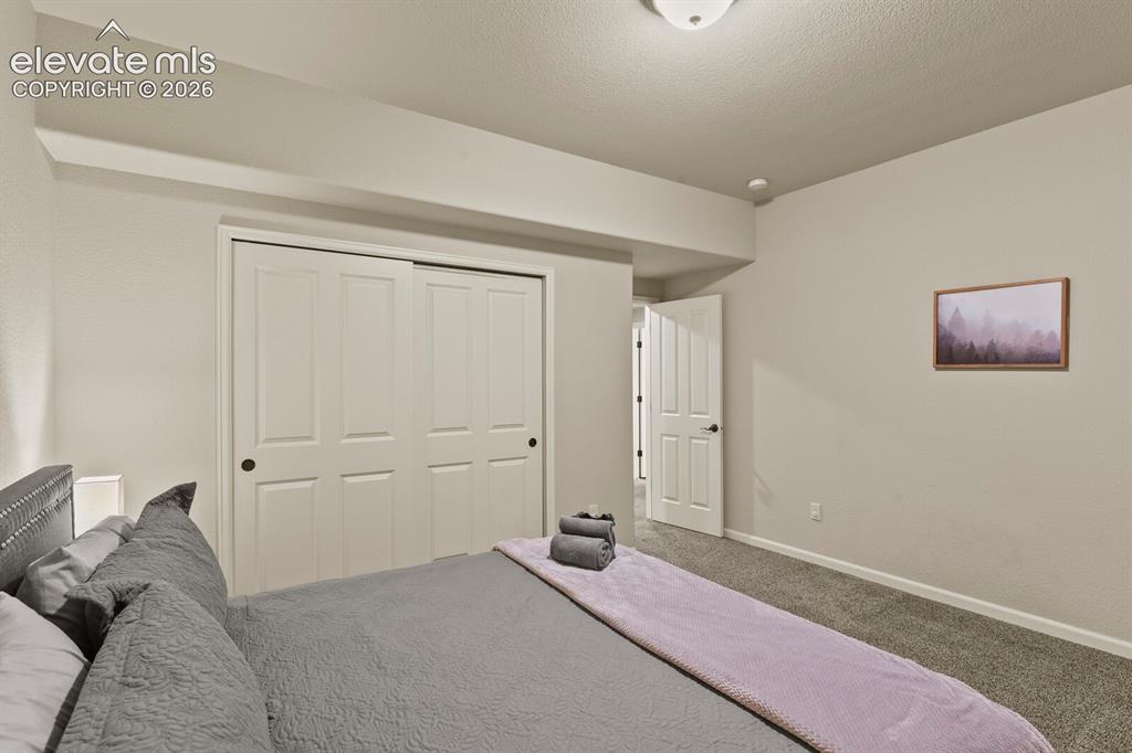 Image 44 of 47: Bedroom featuring a textured carpet floor, neutral wall paint, white trim, 