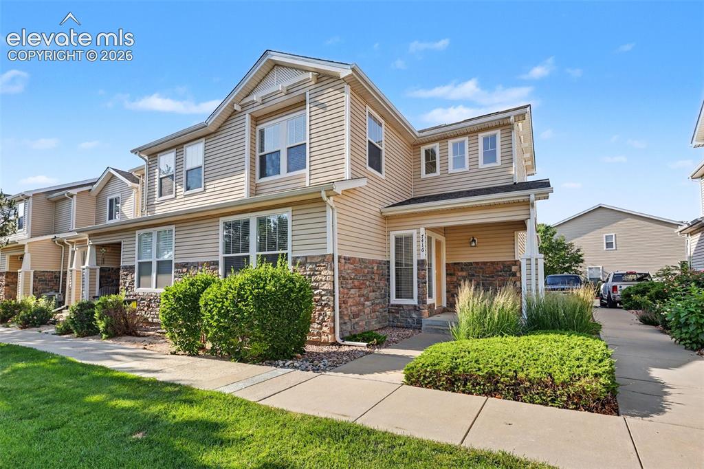 Image 1 of 27: Townhome exterior featuring tan siding and stone veneer accents