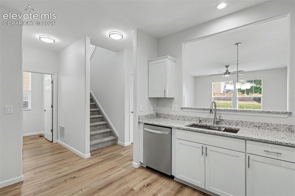 Image 10 of 27: Modern kitchen featuring white shaker cabinetry, granite countertops, stain
