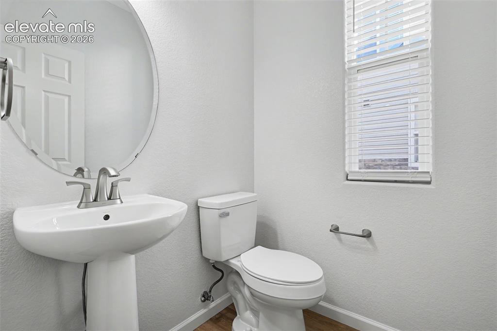 Image 11 of 27: Pedestal sink with a brushed nickel faucet, oval wall mirror, and LVP floor