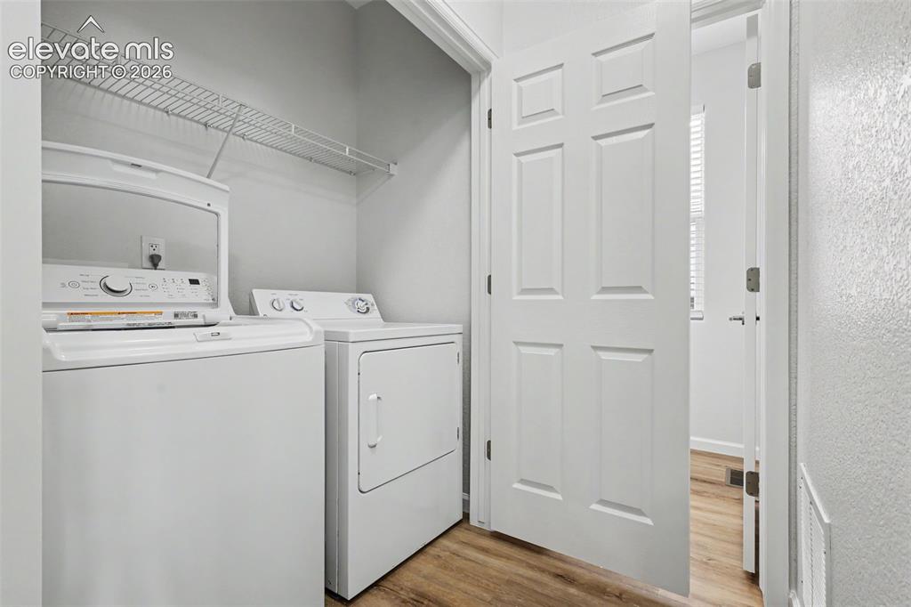 Image 12 of 27: Dedicated laundry area featuring a washer and dryer, LVP flooring, and wire