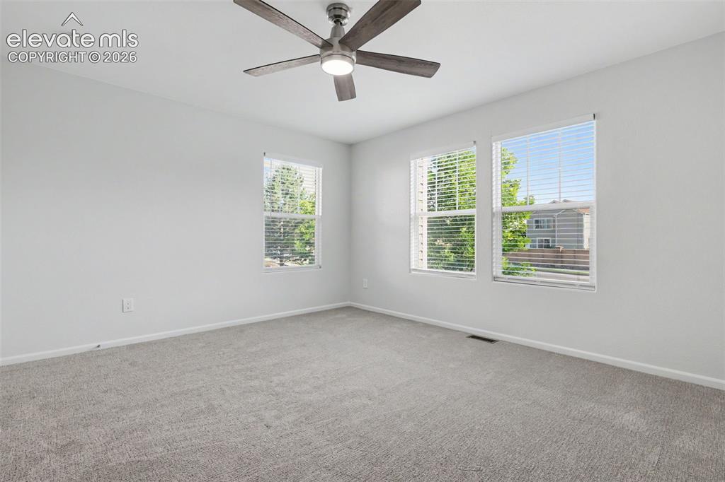 Image 15 of 27: Spacious bedroom with three large windows and ceiling fan
