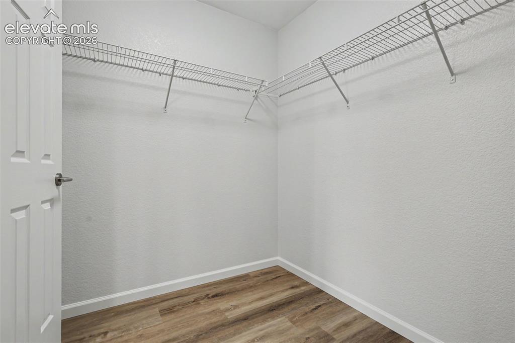 Image 18 of 27: Walk-in closet featuring wire shelving, wood-finish flooring, white baseboa