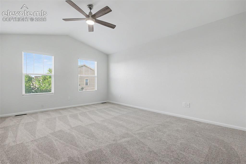 Image 19 of 27: Spacious primary bedroom featuring vaulted ceiling with a ceiling fan