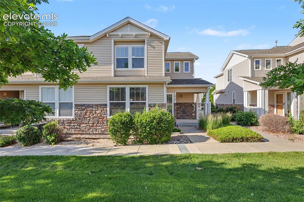 Image 2 of 27: Two-story unit featuring tan siding and stone veneer accents