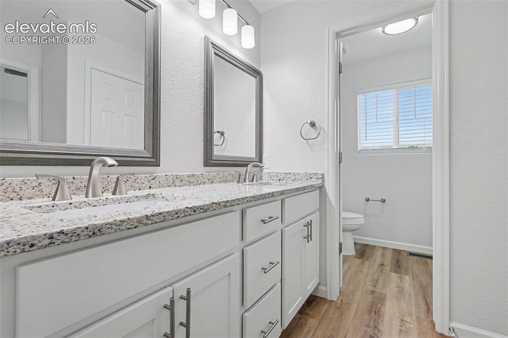 Image 21 of 27: Double vanity with white shaker cabinets and granite countertop and dual un