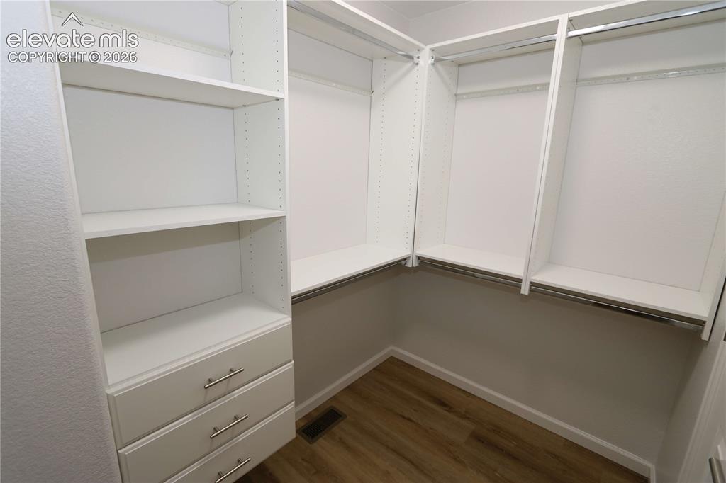 Image 23 of 27: Custom closet system featuring built-in shelving, integrated drawers with b
