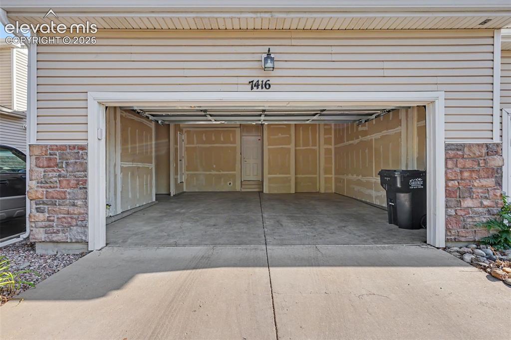 Image 25 of 27: Large attached garage with extra storage area and high ceilings