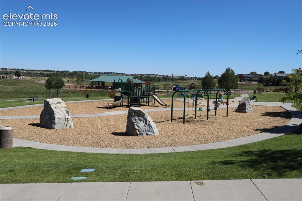 Image 27 of 27: Community park featuring a playground with slides and swings, a covered pic