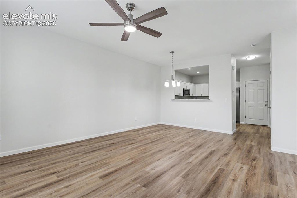 Image 6 of 27: Expansive living area featuring LVP flooring, a ceiling fan with integrated