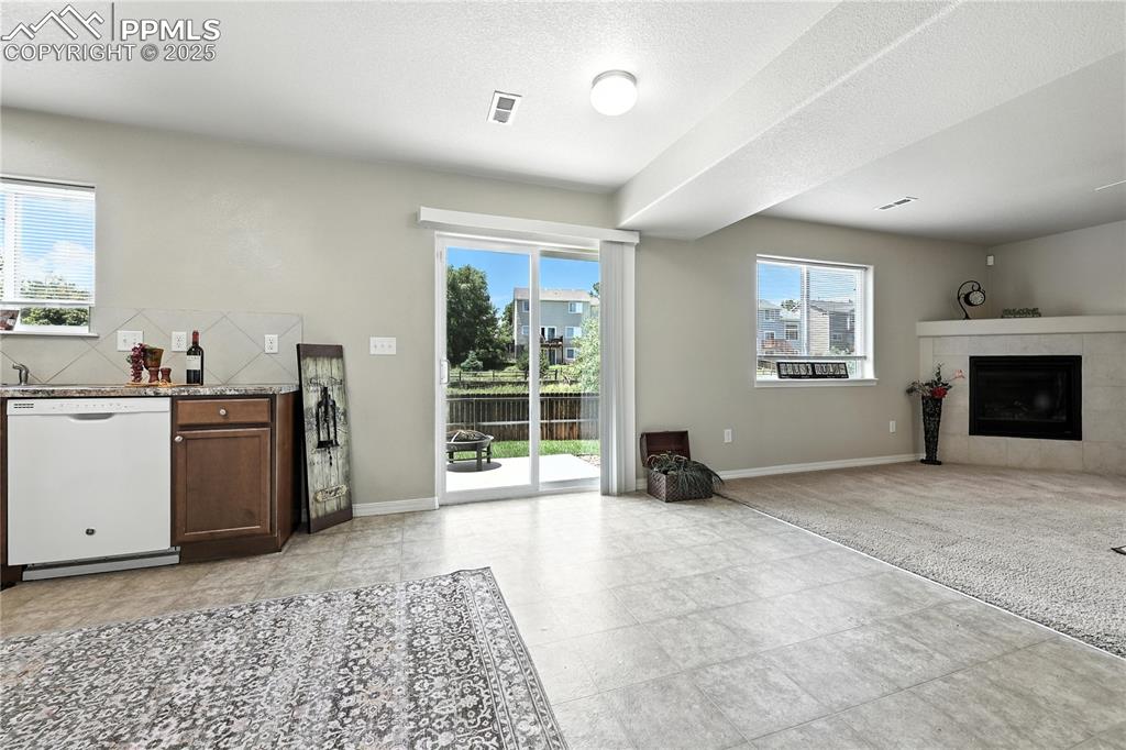 Image 10 of 46: Kitchen featuring dishwasher, open floor plan, and a tiled fireplace