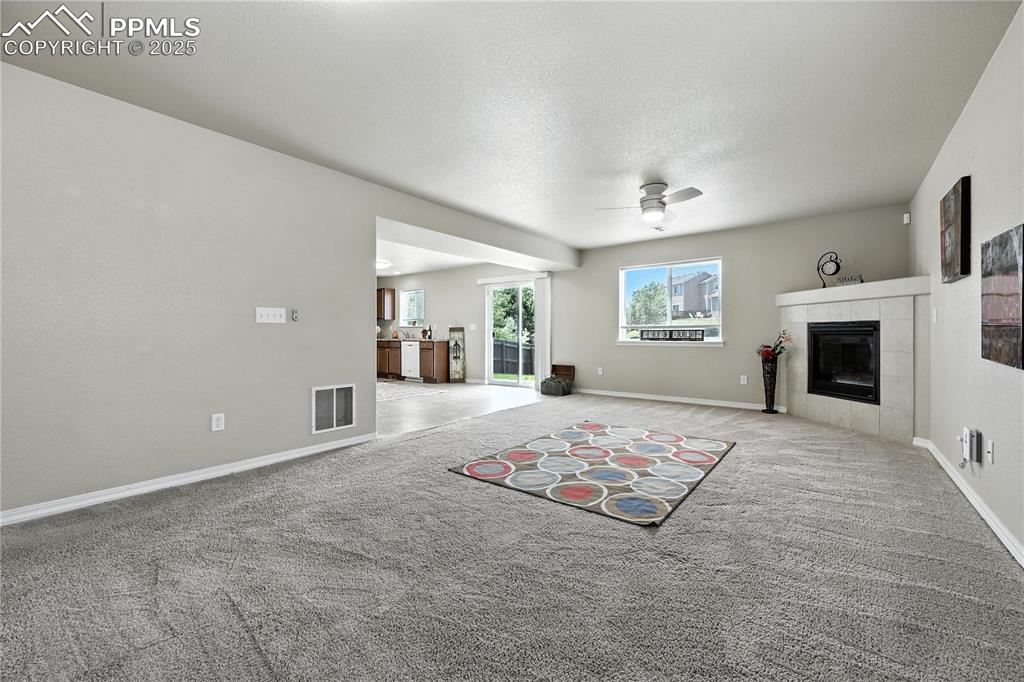 Image 13 of 46: Unfurnished living room with ceiling fan, light carpet, and a fireplace