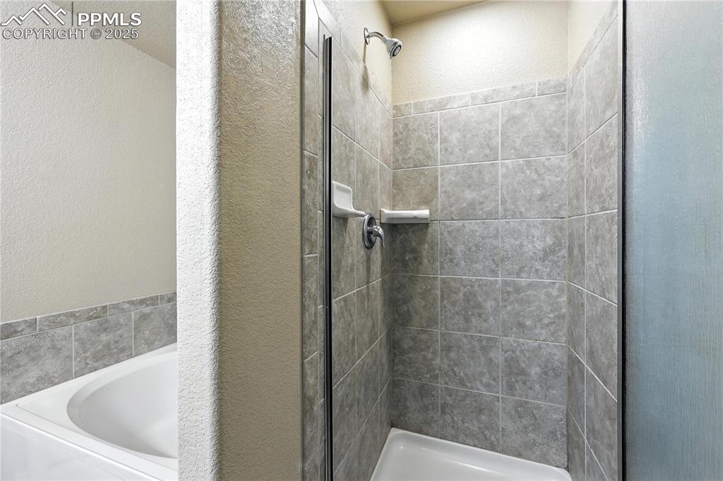 Image 23 of 46: Full bath featuring a garden tub, a stall shower, and a textured wall