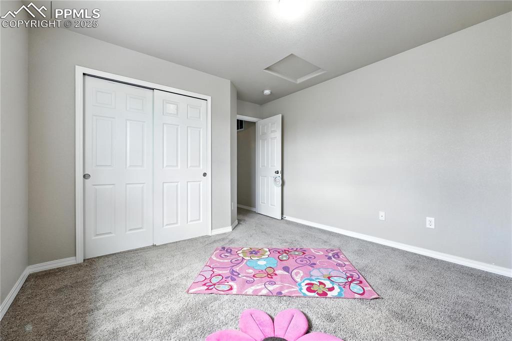 Image 28 of 46: Unfurnished bedroom featuring carpet, attic access, and a closet