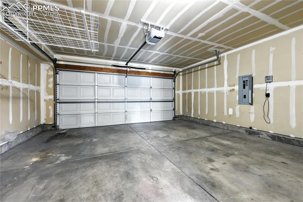Image 29 of 46: Garage with electric panel and a garage door opener