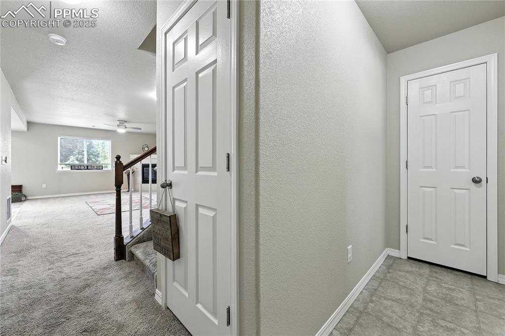 Image 5 of 46: Corridor featuring stairway, a textured wall, and a textured ceiling
