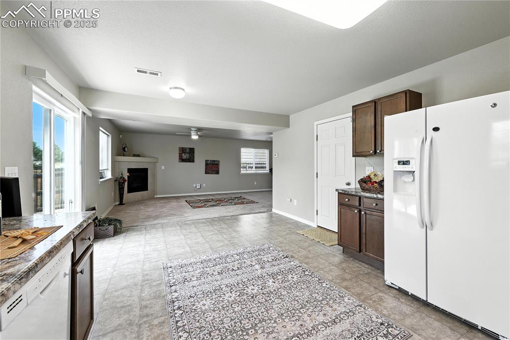 Image 8 of 46: Kitchen with white appliances, ceiling fan, dark brown cabinets, and a tile