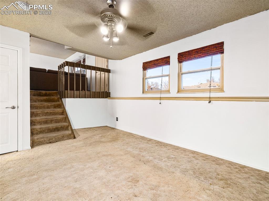Image 10 of 30: Spare room featuring ceiling fan, a textured ceiling, light carpet, a smoke