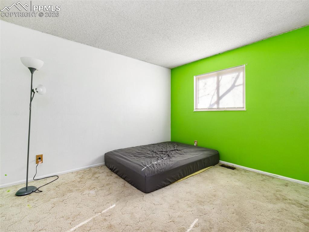 Image 14 of 30: Bedroom with a textured ceiling and carpet floors