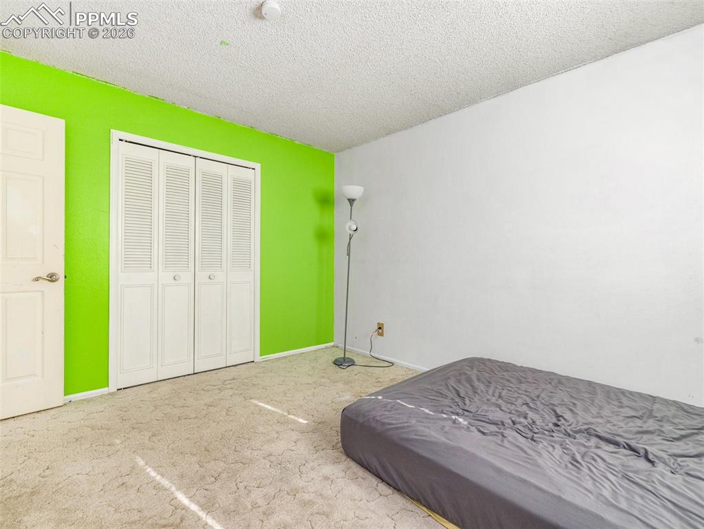 Image 15 of 30: Carpeted bedroom with a textured ceiling and a closet