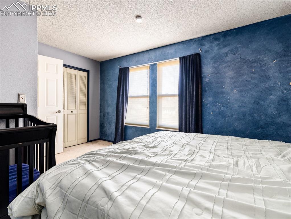 Image 17 of 30: Bedroom featuring a closet, a textured ceiling, and light carpet